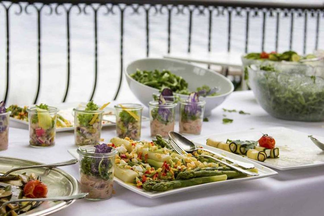 Ein Buffet-Tisch mit verschiedenen Salaten und Gemüse in Gläsern und Schalen.