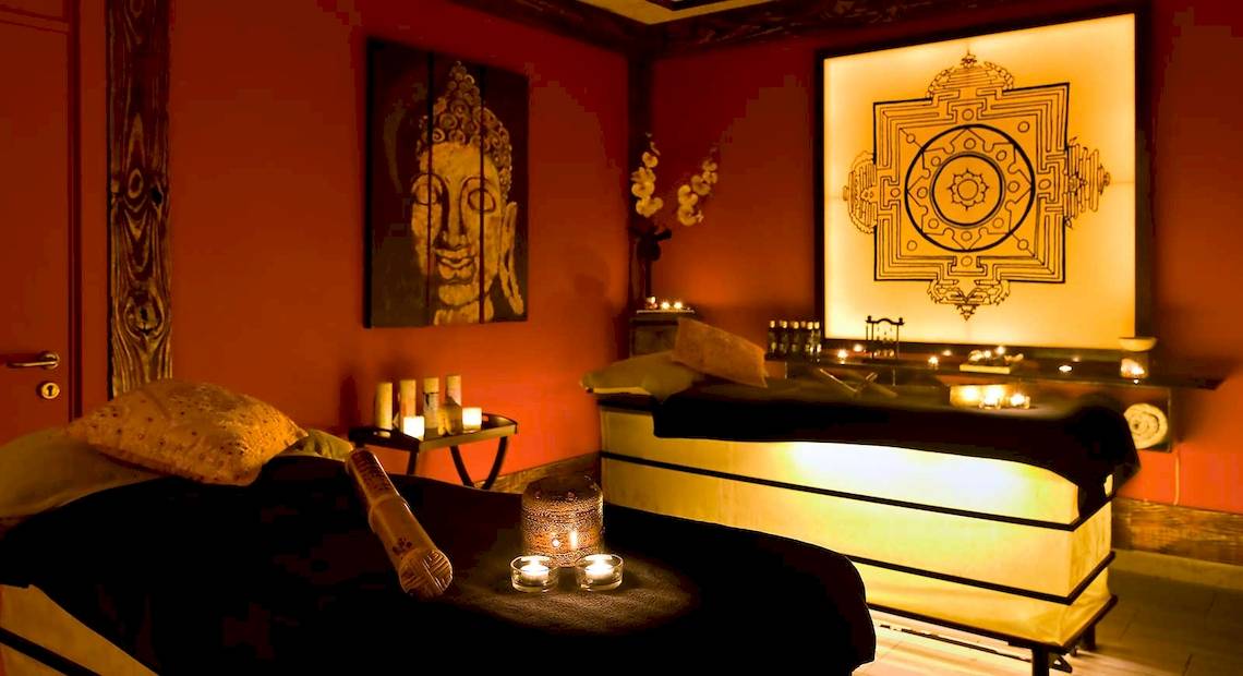 Wellnessbereich im Barcelo Fuerteventura Mar Hotel mit roten Wänden, Kerzen und einem Buddha-Gemälde.