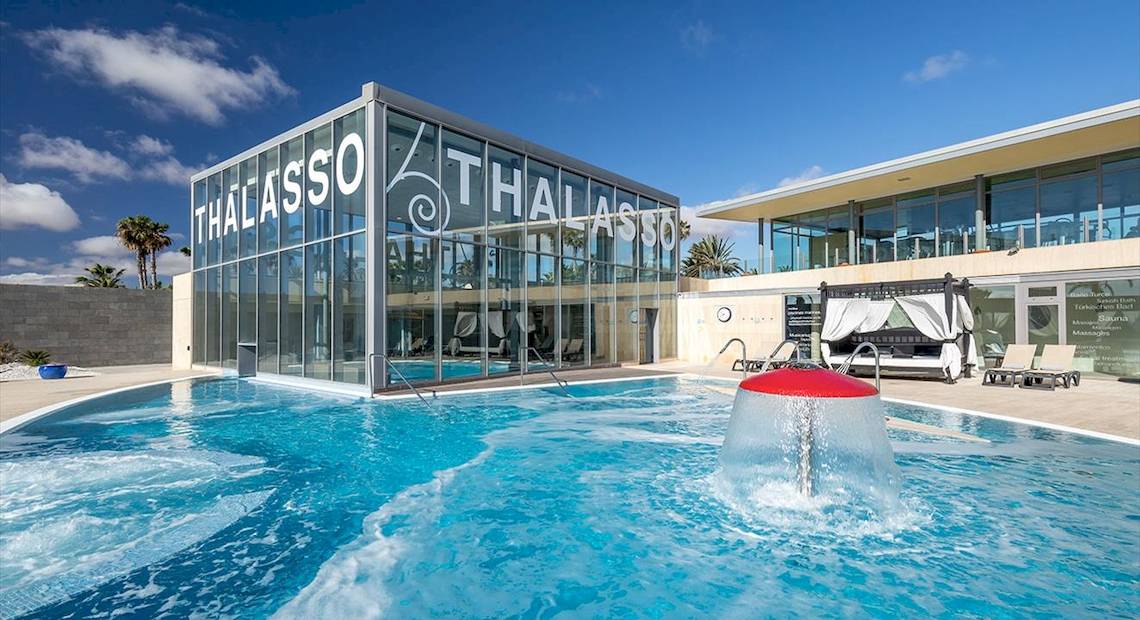 Außenpool des Barcelo Fuerteventura Mar Thalasso Hotels mit modernem Glasgebäude im Hintergrund.