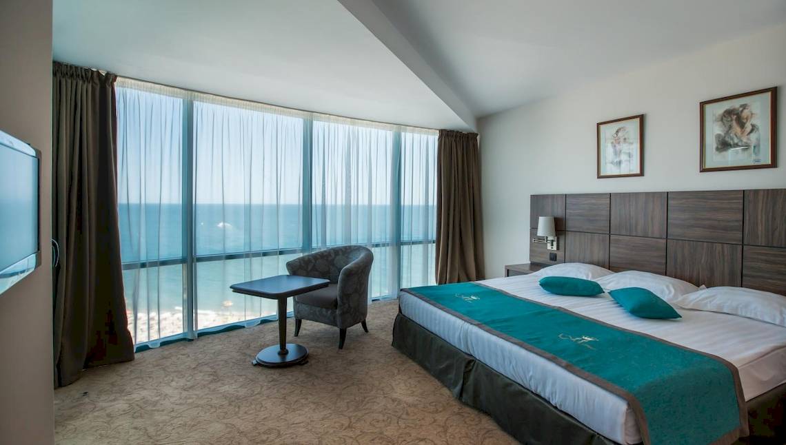 Hotelzimmer des Marina Grand Beach mit Meerblick, inklusive Bett, Tisch, Stuhl und Fernseher.