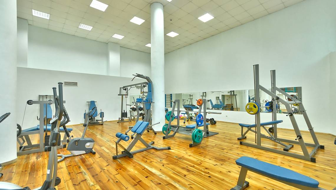 Fitnessstudio im Marina Grand Beach Hotel mit verschiedenen Trainingsgeräten und einem großen Spiegel.