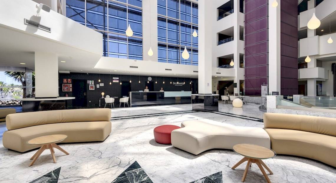 Lobby des Barcelo Lanzarote Active Resort mit moderner Einrichtung, großen Fenstern und Sitzbereichen.