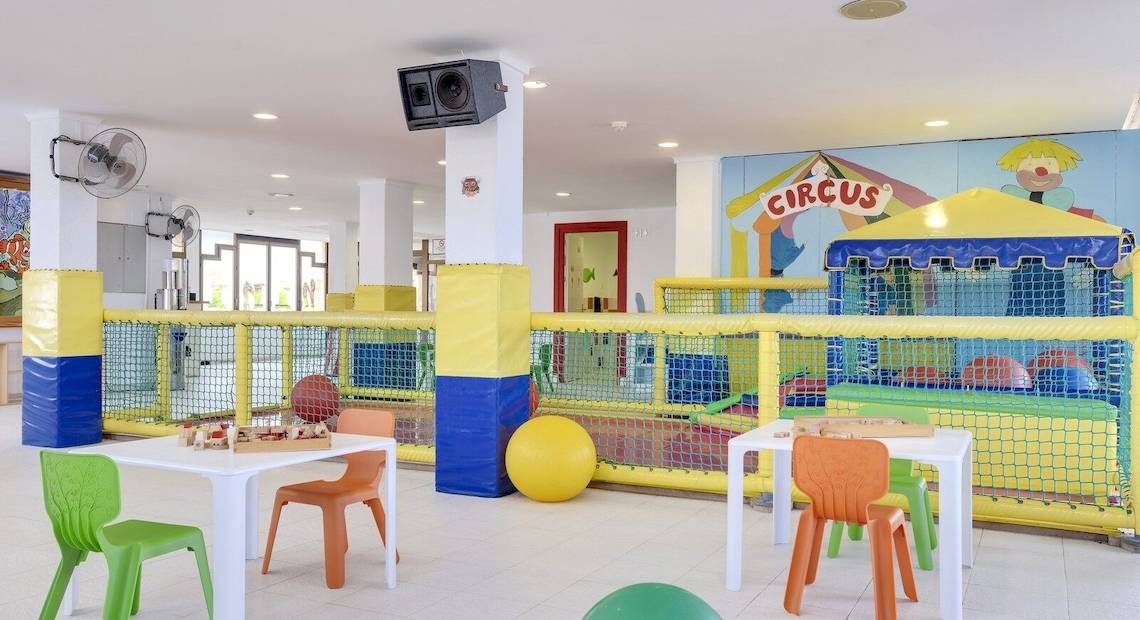 Spielplatz im Barcelo Lanzarote Active Resort mit bunten Tischen, Stühlen und einem großen gelben Ball.