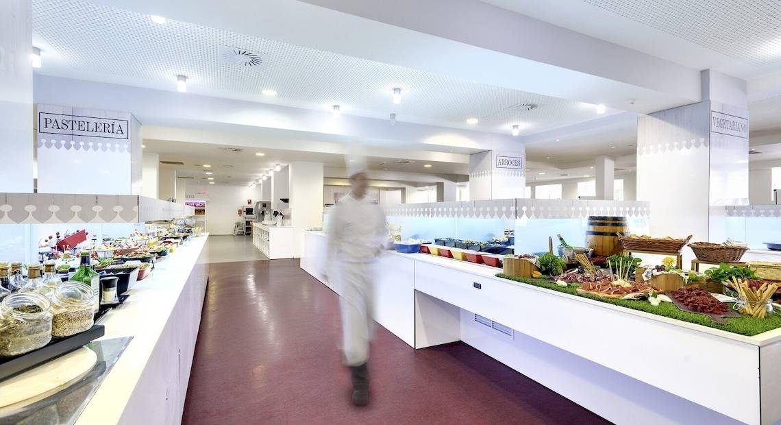 Restaurantbereich des Barcelo Lanzarote Active Resort mit einer Theke voller Speisen und einem Koch in weißer Kleidung, der sich entfernt.