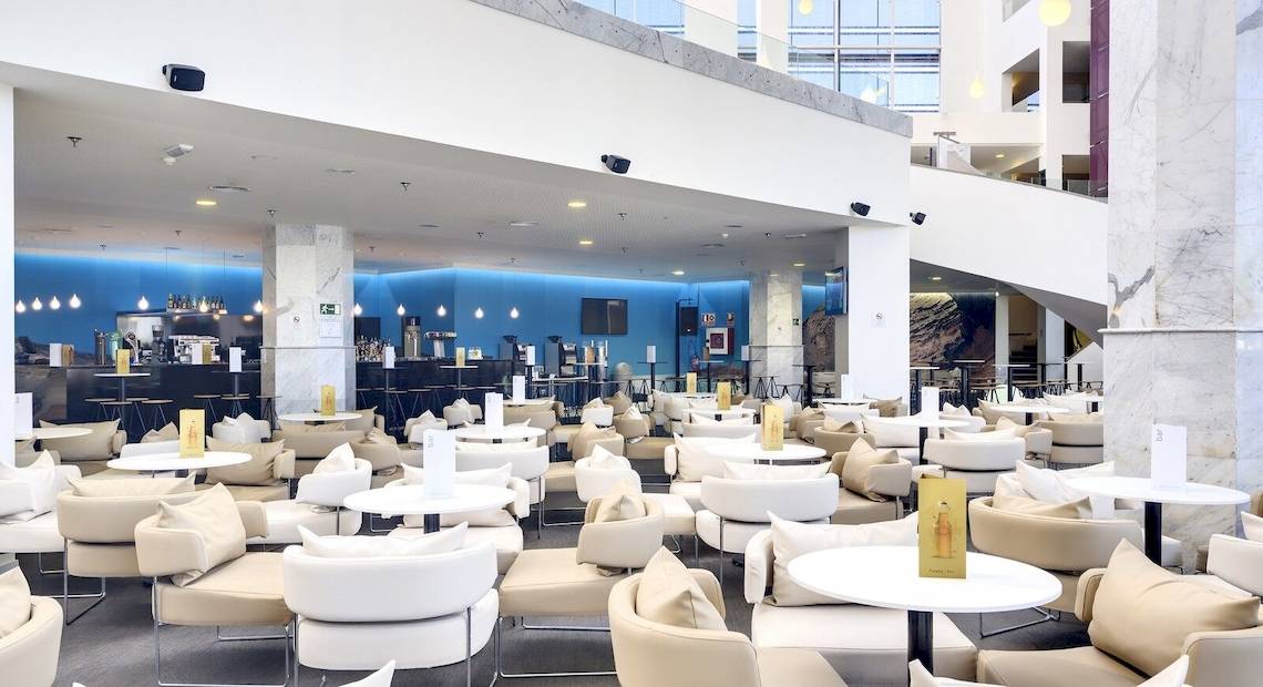 Loungebereich des Barcelo Lanzarote Active Resort mit vielen weißen Tischen und Stühlen.