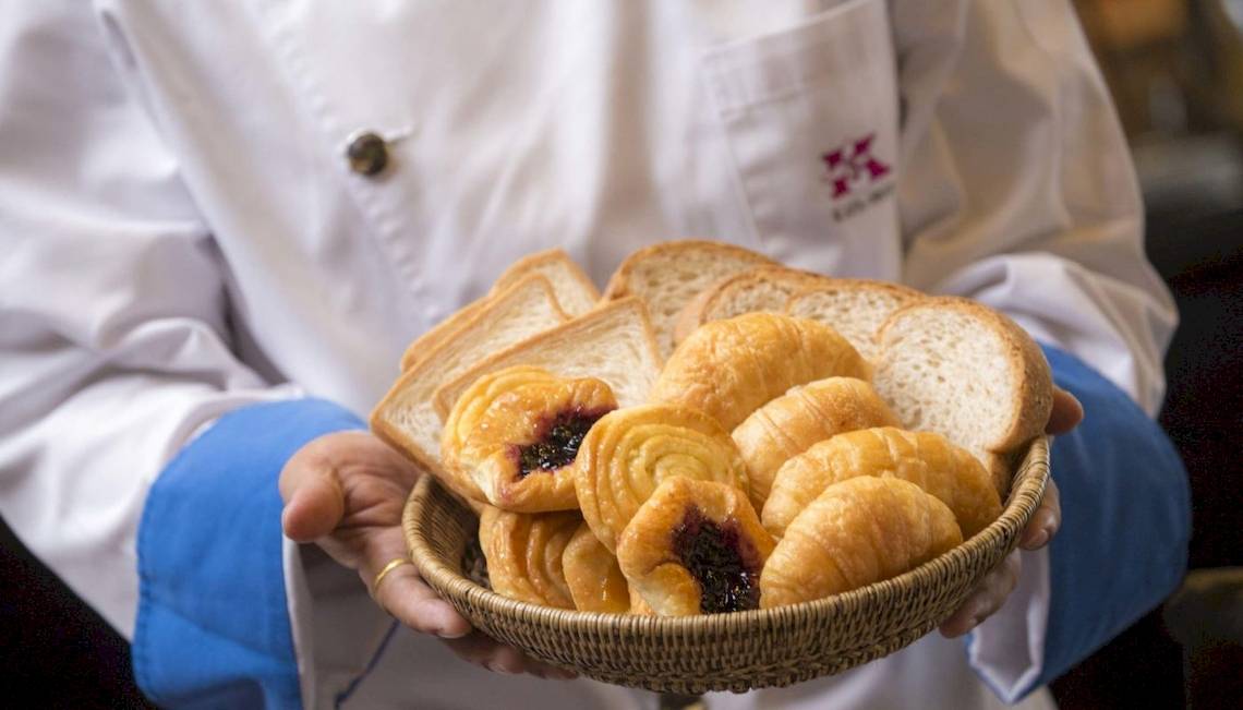 Ein Mitarbeiter des Beyond Resort Krabi hält eine Schale mit Croissants und Brötchen.