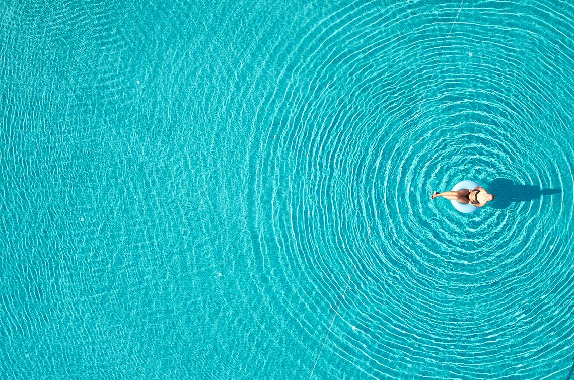 Frau im Pool von oben gesehen, die auf einem Schwimmring liegt.
