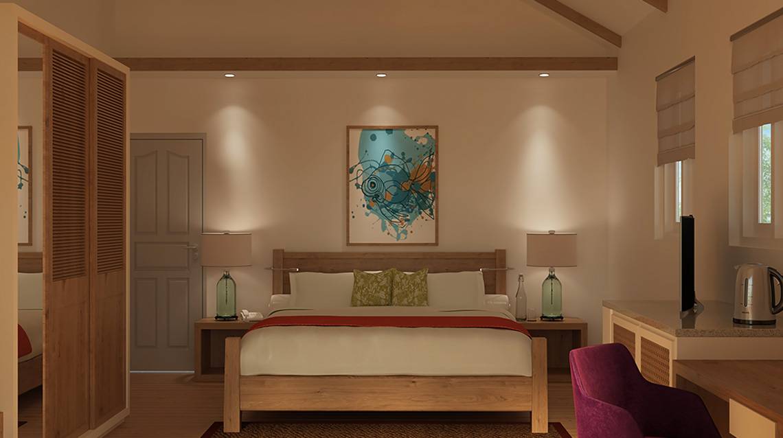 Innenansicht eines Schlafzimmers im Ellaidhoo Maldives by Cinnamon Hotel mit einem großen Bett, Gemälde an der Wand, Nachttischen und Lampen.