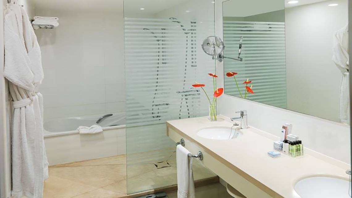 Badezimmer im H10 Gran Tinerfe Hotel mit Badewanne, Waschbecken und Spiegel.