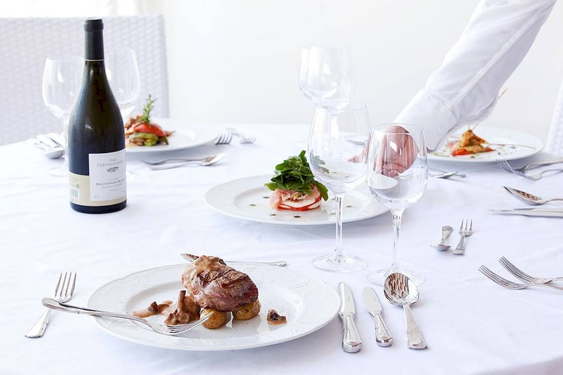 Dinnertisch im Lindos Bay Hotel mit Speisen, Wein und Geschirr