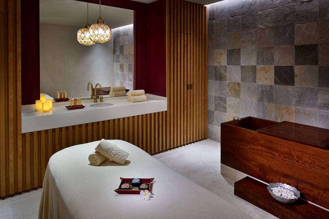 Spa-Behandlungsraum im Raffles The Palm Dubai mit Massageliege, Badewanne und luxuriöser Ausstattung.