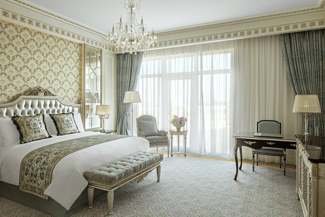 Schlafzimmer im Raffles The Palm Dubai mit großem Bett, Kristallkronleuchter, und Schreibtisch