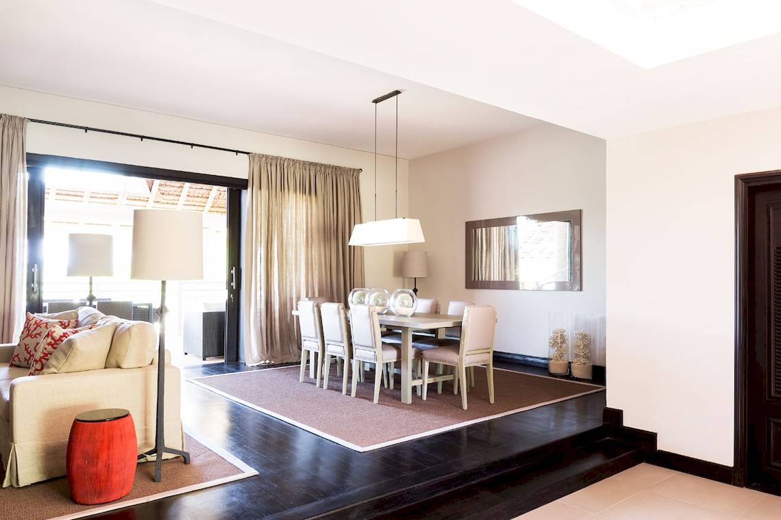 Wohnzimmer im LUX Belle Mare Resort & Villas mit Esstisch, Stühlen, Teppich, Lampe und Sofa.
