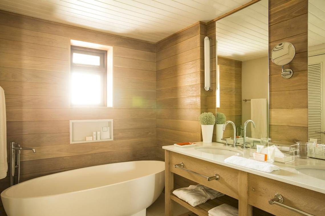 Badezimmer im LUX Belle Mare Resort & Villas mit Badewanne, Waschbecken und Spiegeln.