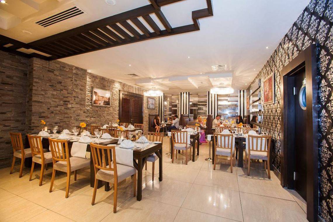 Innenansicht des Restaurants im Orange County Belek Hotel mit gedeckten Tischen und dekorierten Wänden.