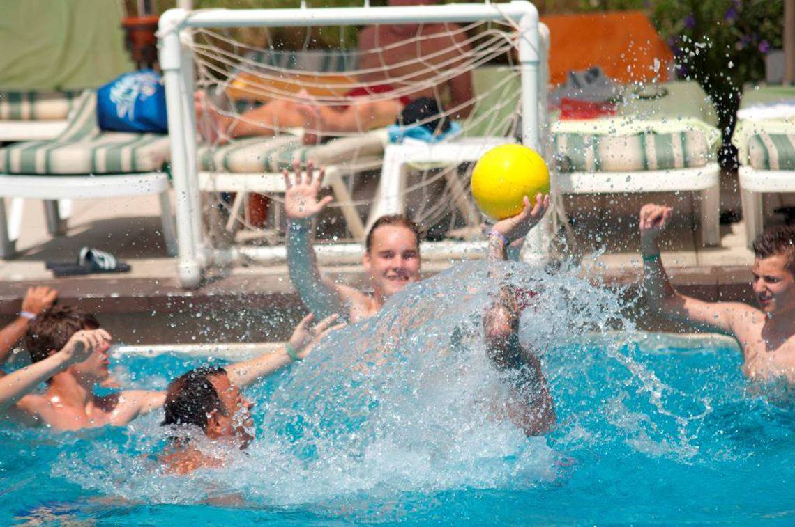 Gruppe junge Leute spielen Ball im Schwimmbad Orange County Belek