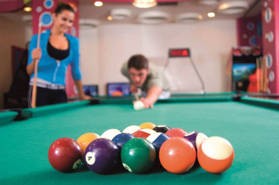 Mann spielt Billard im Hotel Orange County Belek, Frau schaut zu.
