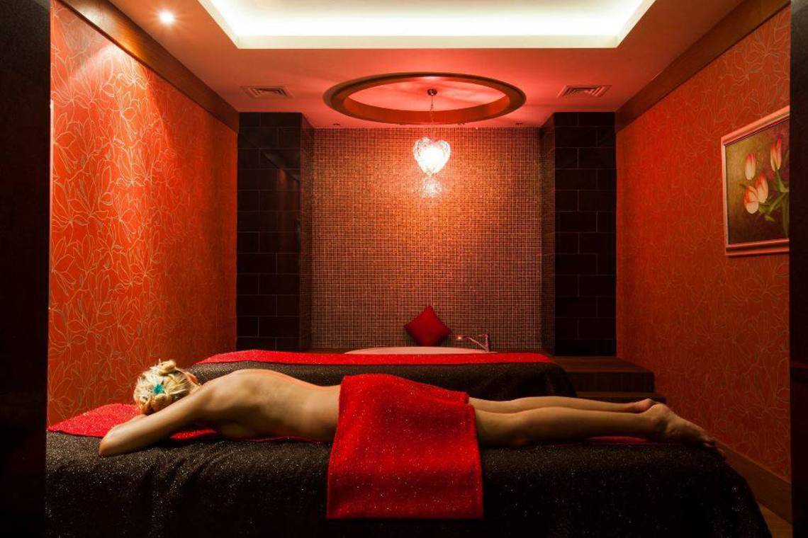 Ein roter Raum mit Spa-Betten, einer Frau, die sich entspannt und einem Herz-Licht.