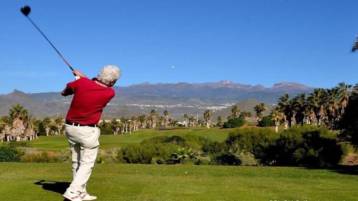 Golfspieler schlägt auf einem Golfplatz mit Bergen im Hintergrund