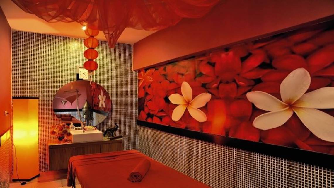 Spa-Behandlungsraum im Seaden Corolla Hotel mit rotem Dekor, großen Blumentapeten und Entspannungsmöbeln.