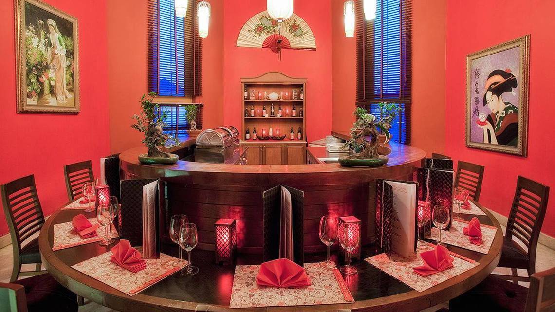 Innenansicht eines Rundtisches im Barbereich des Kremlin Palace Hotels, dekoriert mit roten Servietten, Weinläsern und Pflanzen.