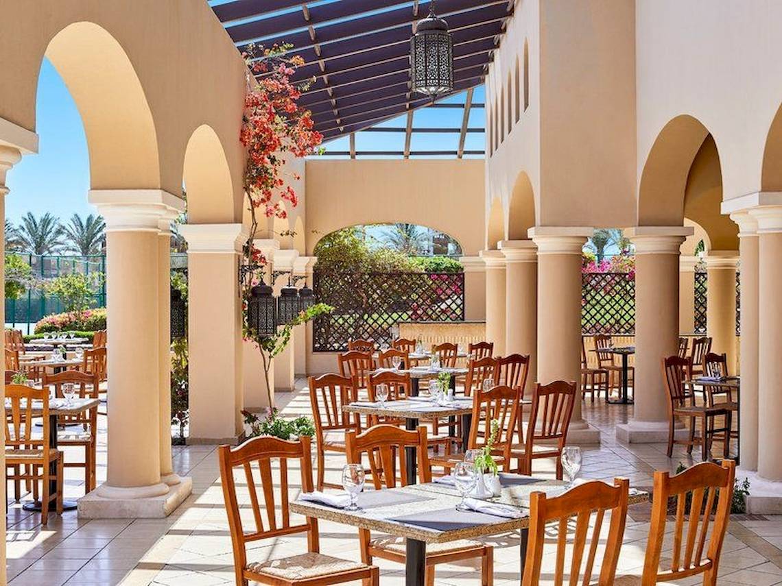 Restaurantbereich des Jaz Mirabel Beach Hotels mit freien Tischen und Stühlen unter einem Dach.