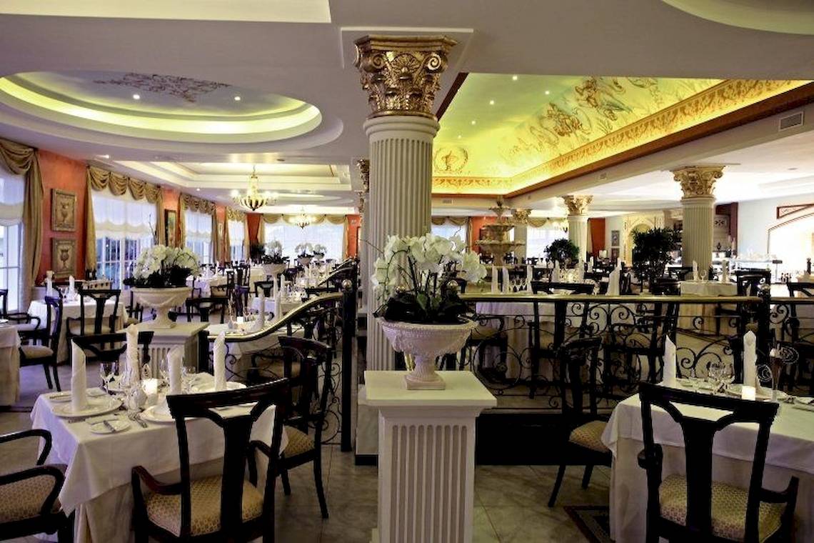 Innenansicht des Restaurants im Bahia Principe Luxury Esmeralda Hotel mit gedeckten Tischen, eleganten Stühlen und dekorativen Säulen.