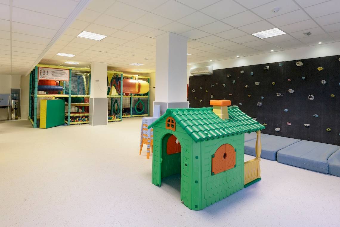 Spielbereich für Kinder im Leonardo Royal Hotel Ibiza Santa Eulalia mit Kletterwand, Spielhaus und Spielzeug.