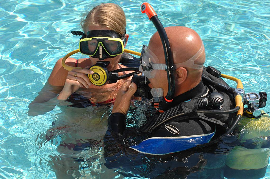 Eine Frau und ein Mann tauchen im Schwimmbecken des Marti Resorts, beide tragen Tauchausrüstung.