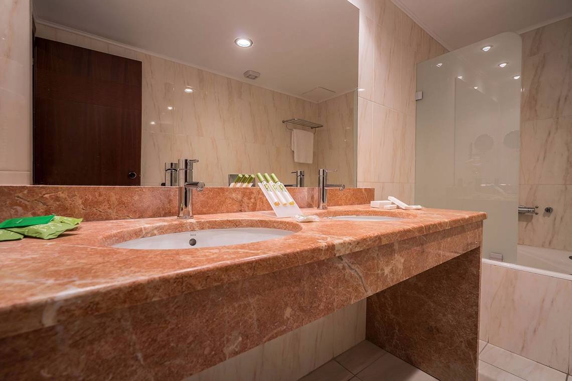Badezimmer im Galaxy Beach Resort mit Marmorwaschtischen, Spiegel und Badewanne.