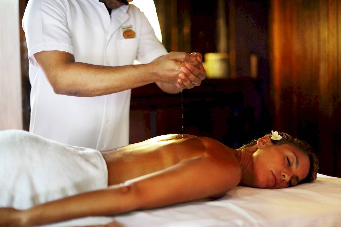 Massage im Gangehi Island Resort, wo eine Frau eine Rückenmassage genießt.