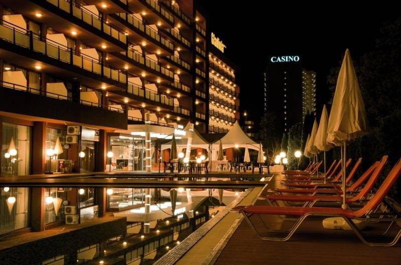 Poolbereich des Gladiola Star Hotels bei Nacht mit beleuchteten Liegestühlen und Gebäuden.