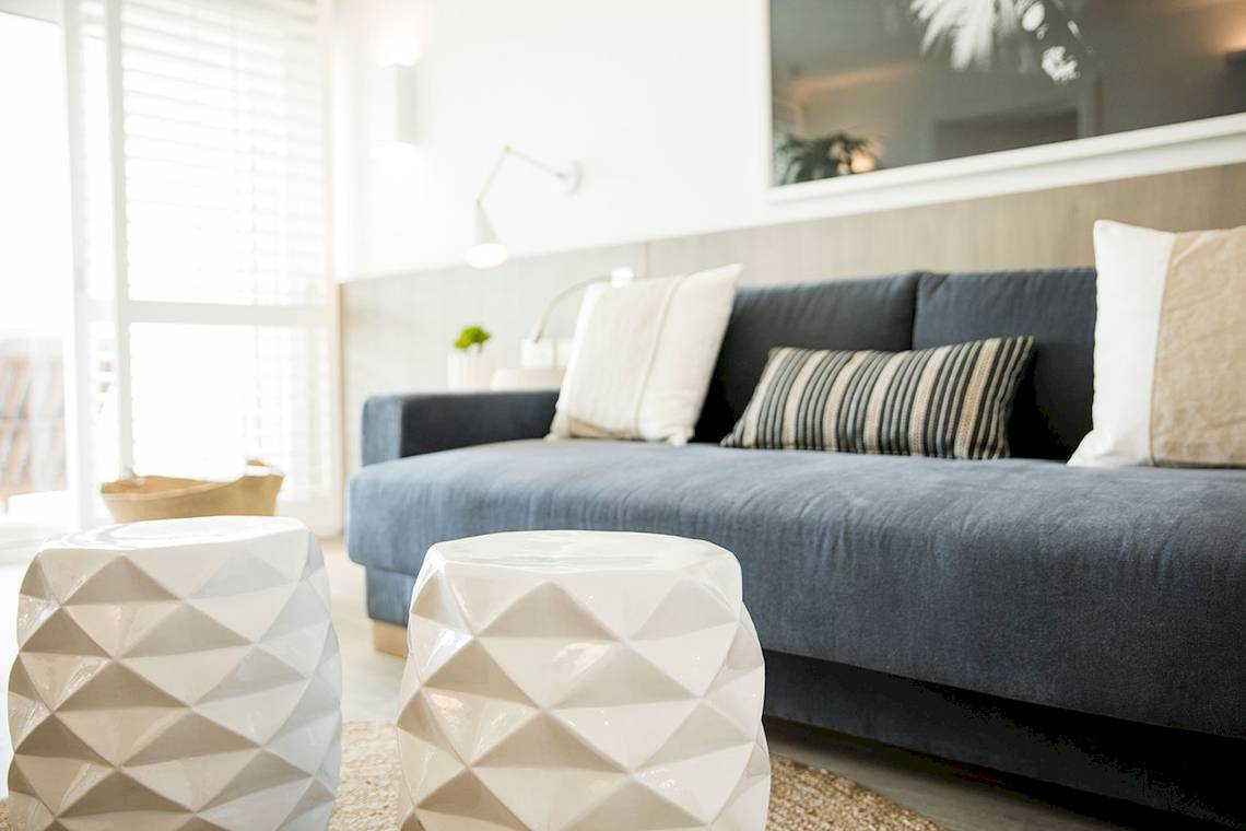 Wohnbereich im LUX Grand Gaube Resort & Villas mit grauem Sofa, weißen Beistelltischen und einem gerahmten Bild an der Wand.