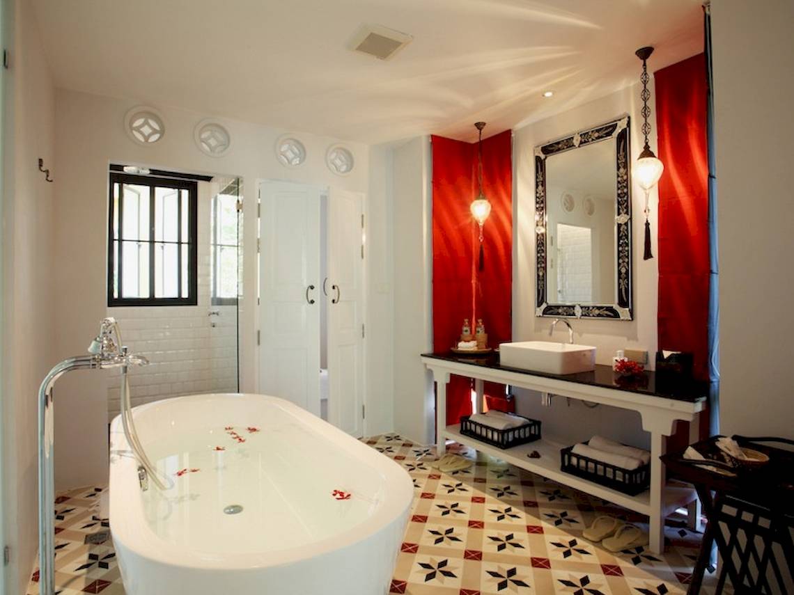 Badezimmer im Moracea by Khao Lak Resort mit Badewanne, Waschbecken und rotem Wanddesign.