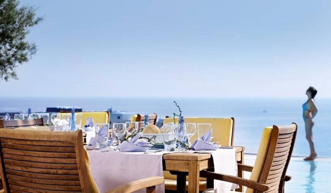 Außenbereich des Esperos Village Blue & Spa Hotels mit Tisch und Stühlen am Pool.