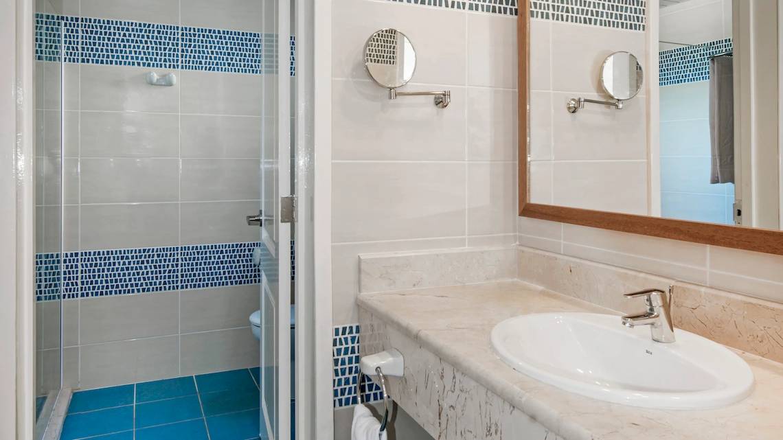 Badezimmer im Iberostar Tainos Hotel mit blauen Fliesen und Spiegeln.