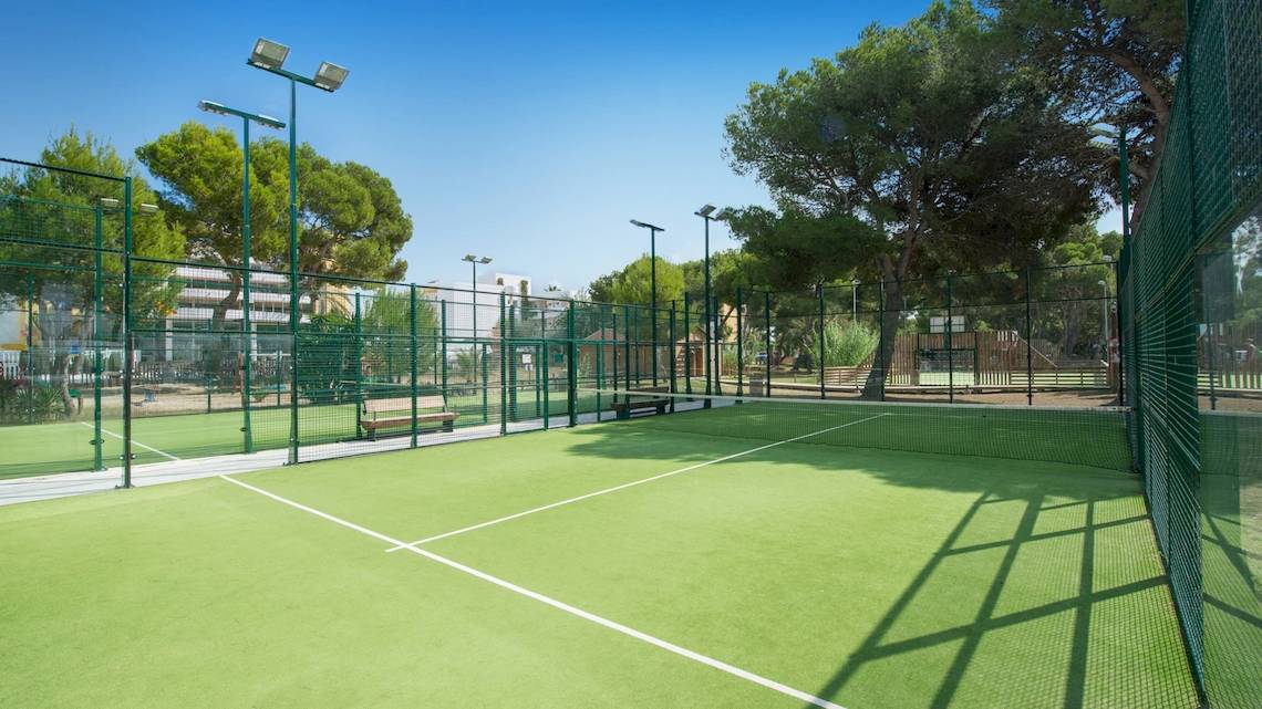 Tennisplatz im Freien im Iberostar Selection Albufera Playa Hotel mit umzäuntem Bereich und Bäumen im Hintergrund.