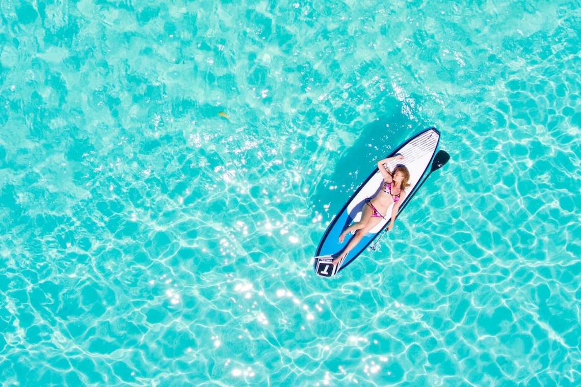 Frau im Bikini auf einem Surfbrett im Wasser, Villa Park, Maldives