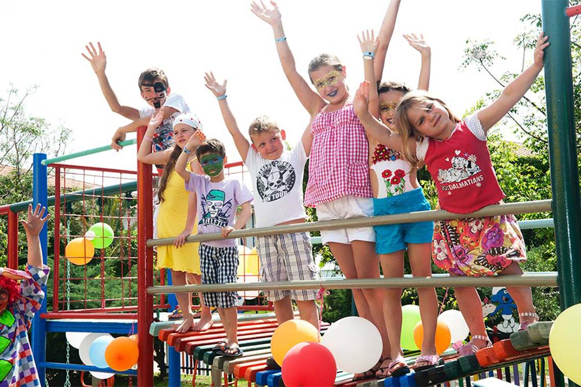 Mehrere Kinder stehen auf einem Spielplatz im Belconti Resort, alle haben Gesichtsbemalungen und posieren für ein Foto.