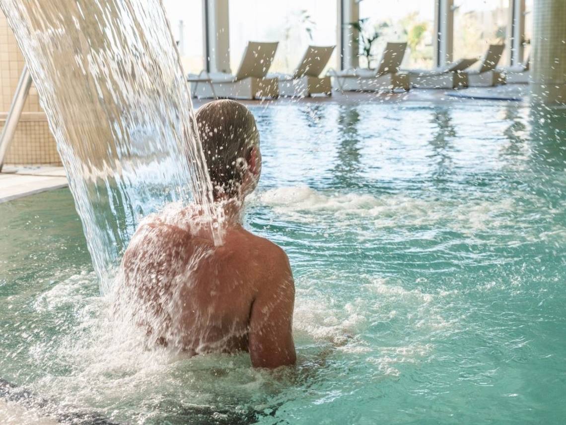 Mann im Pool unter einem Wasserfall im Secrets Bahia Real Resort & Spa