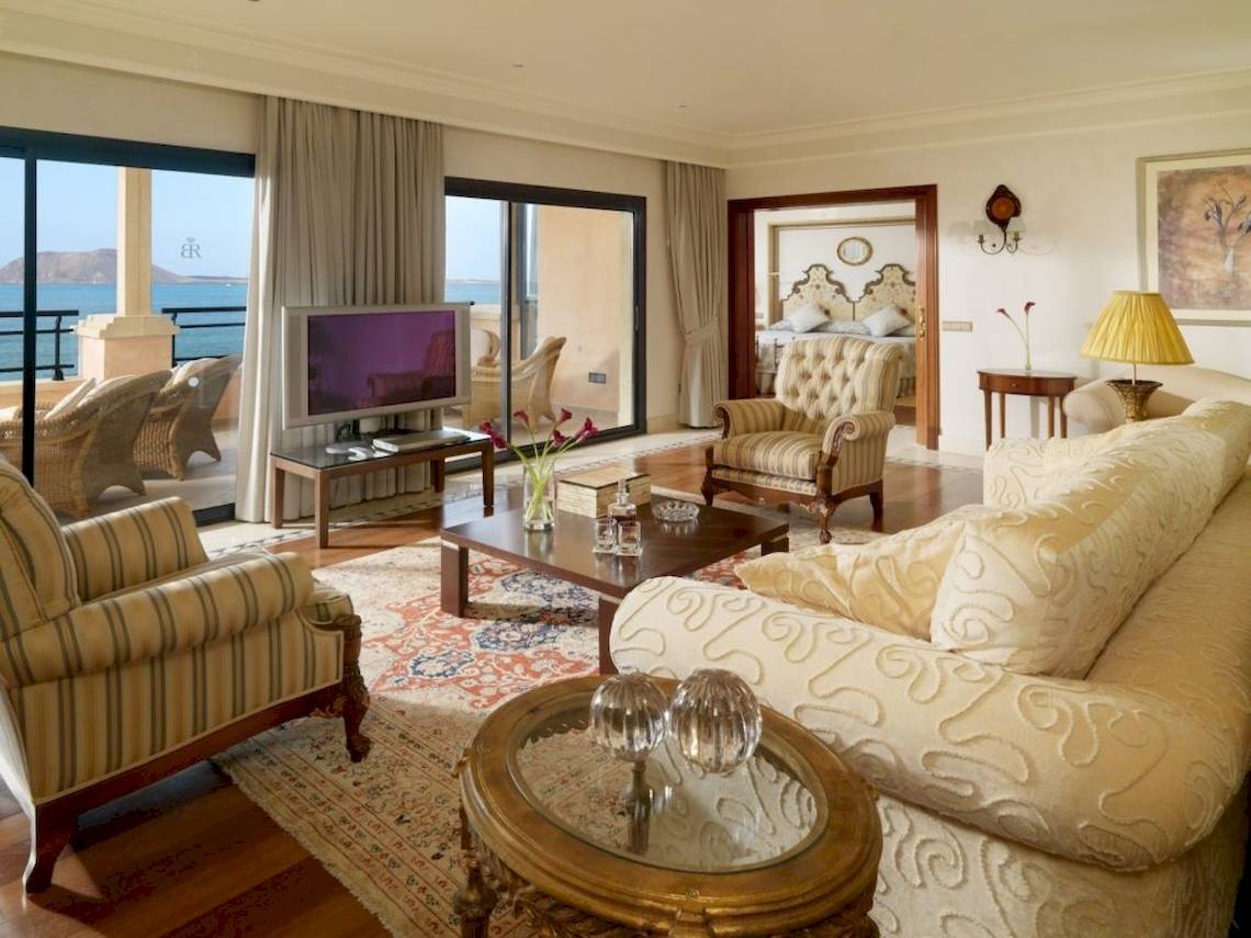 Wohnzimmer im Secrets Bahia Real Resort & Spa mit Meerblick, Fernseher, Sofa, Tisch und Dekor.