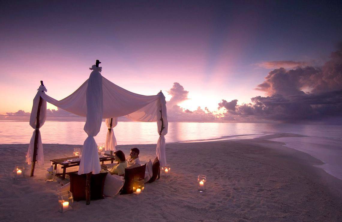 Zwei Personen genießen ein Abendessen unter einem Zelt am Strand des Waldorf Astoria Dubai Palm Jumeirah.