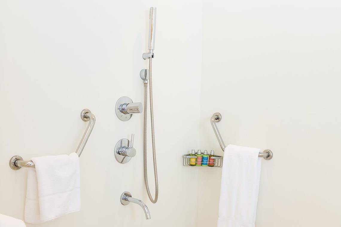 Barrierefreie Dusche im Capo Bay Hotel mit Handtüchern und Haltegriffen.