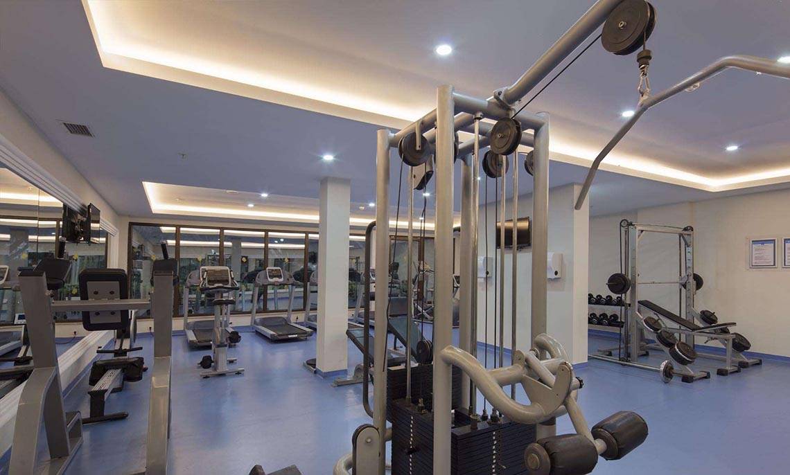 Fitnesscenter im Magic Life Belek Hotel mit verschiedenen Trainingsgeräten und blauen Böden.