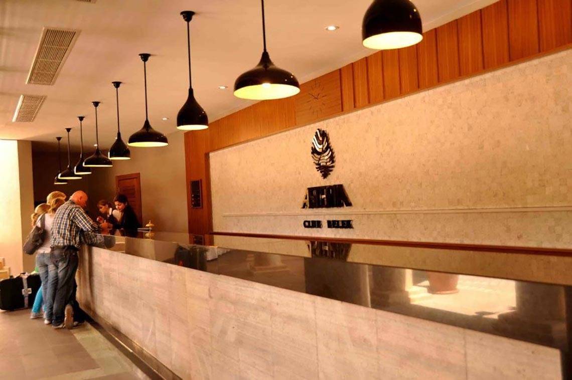 Empfangsbereich des Magic Life Belek Hotels mit Personen an der Rezeption und stilvollen Beleuchtung.
