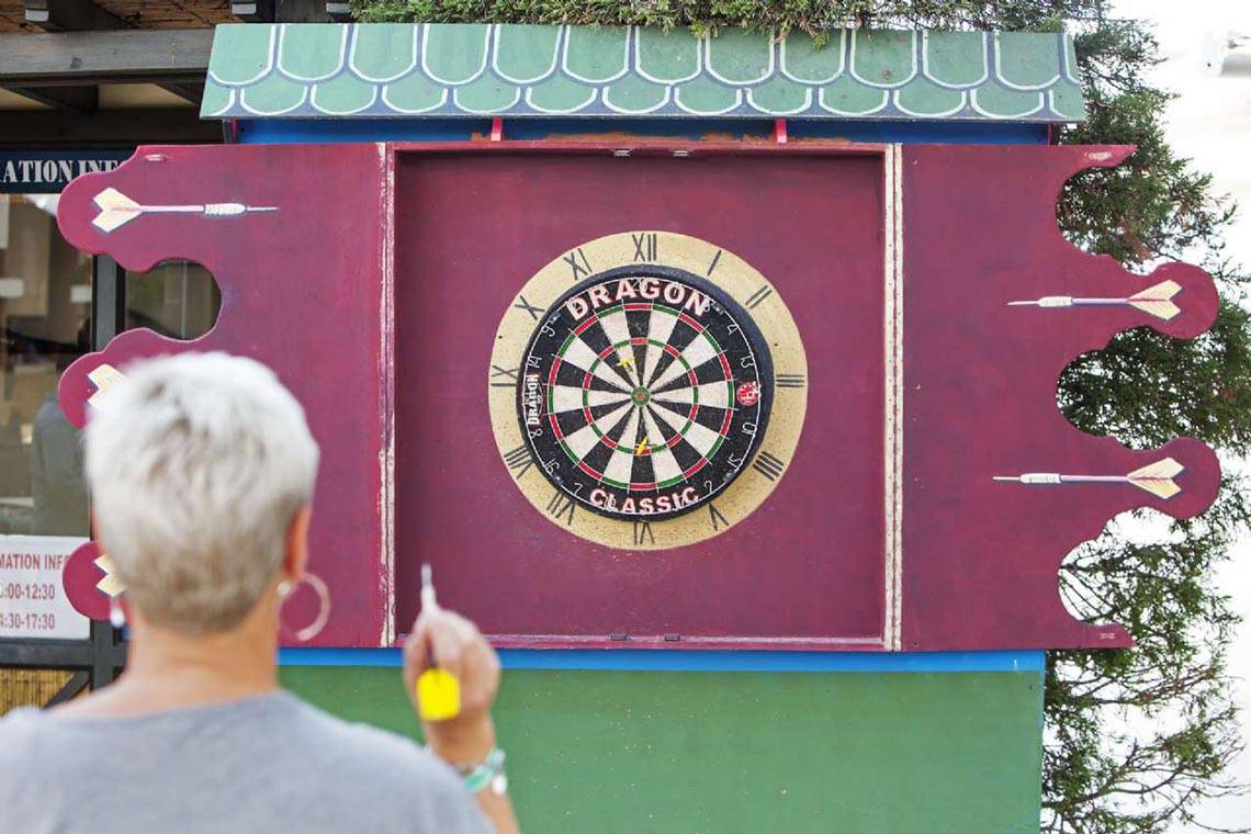 Eine Person spielt Darts vor einem Dragon Dartboard.