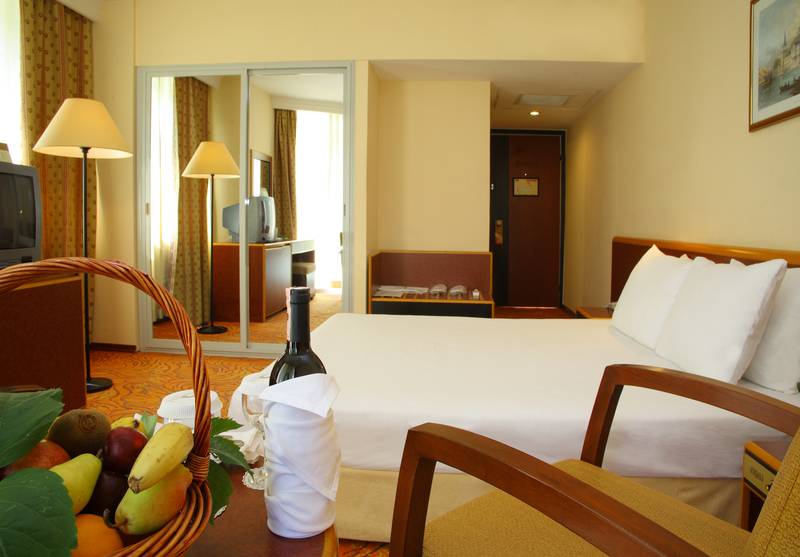 Hotelzimmer im Palm Wings Ephesus Beach Resort mit Bett, Obstkorb und Weinflasche.