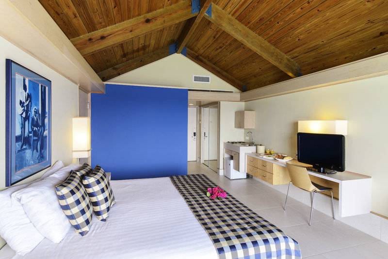 Innenansicht eines Zimmers im Avila Beach Hotel mit Bett, Schreibtisch, Fernseher und blauer Wand.