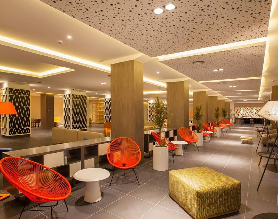 Innenbereich des Abora Catarina Hotel mit roten Stühlen und Tischen, Pflanzgefäßen und gefliestem Boden.