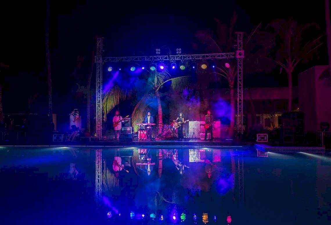 Ein abendliches Konzert am Pool des Kandima Maldives Hotels mit bunten Lichtern und Musikern auf der Bühne.